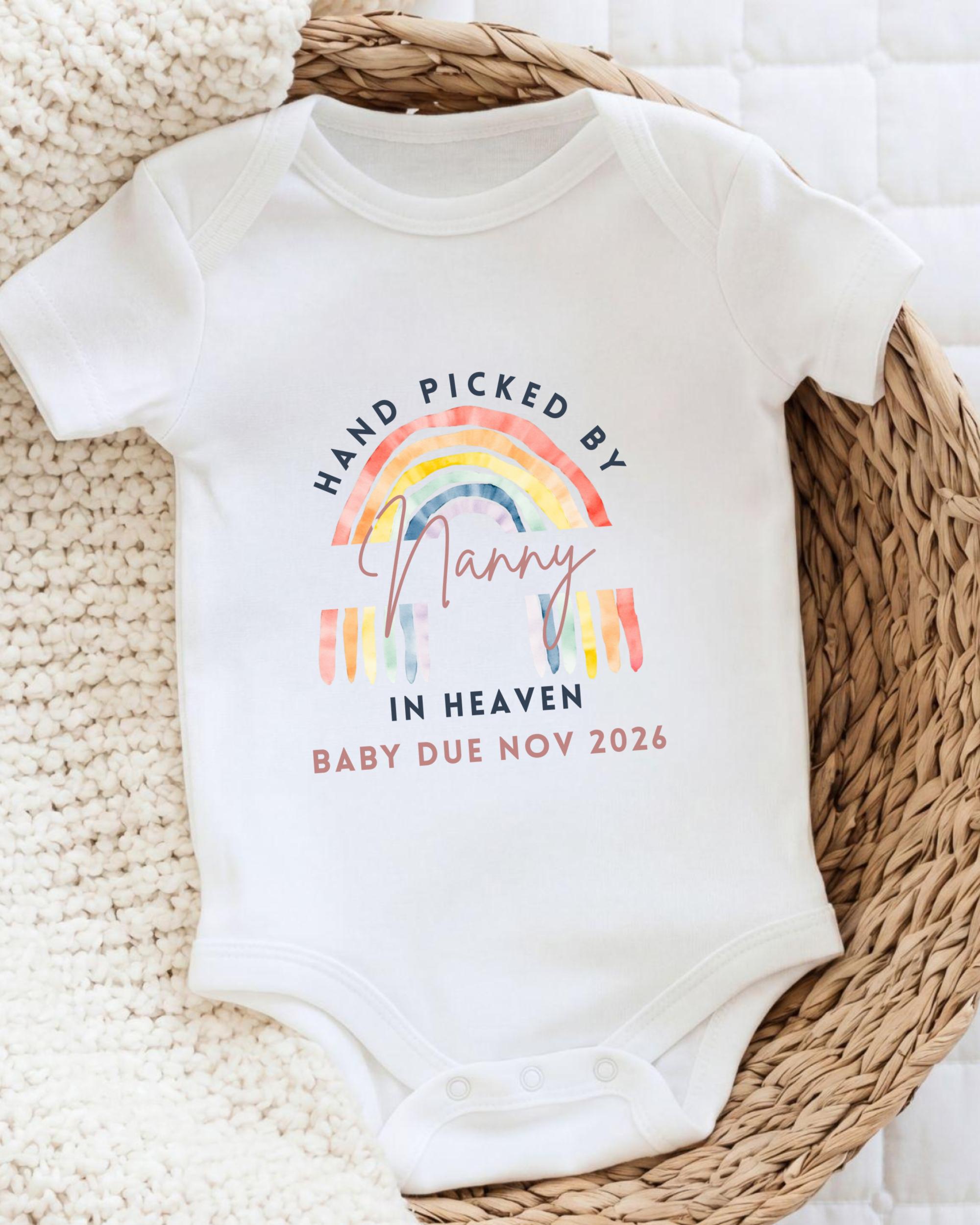 A white baby onesie with a rainbow graphic and text that reads "Hand picked by Nancy in Heaven Baby Due Nov 2026".