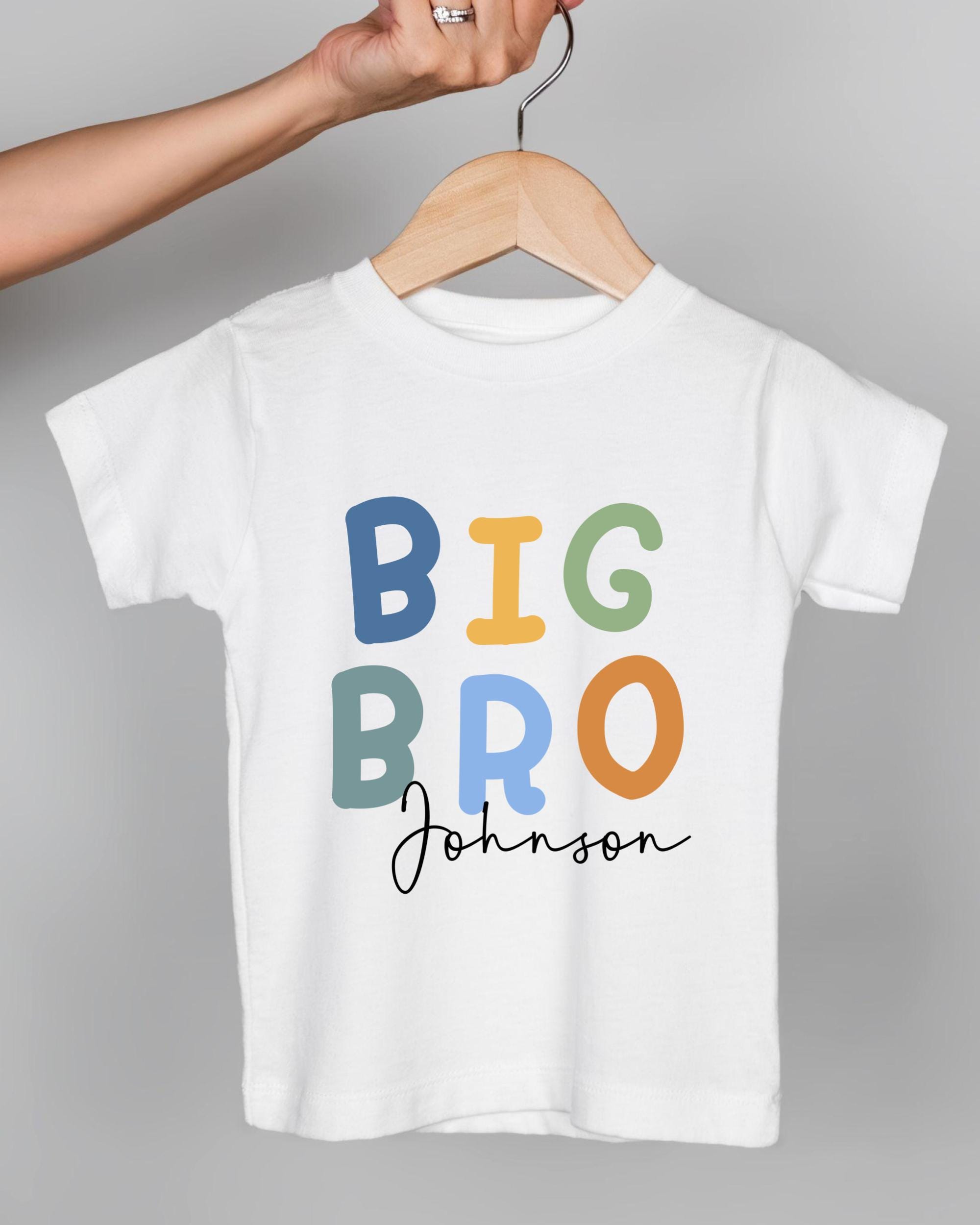 A person's hand is holding a white t-shirt with the text "BIG BRO Johnson" printed on it.