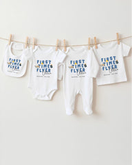 A row of four white baby clothes, including onesies and pajamas, hanging on a clothesline.