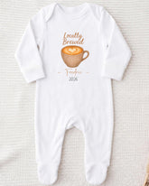 A white onesie with a graphic of a cup of coffee and the text "Locally Brewed Fredricine 2026" printed on it.