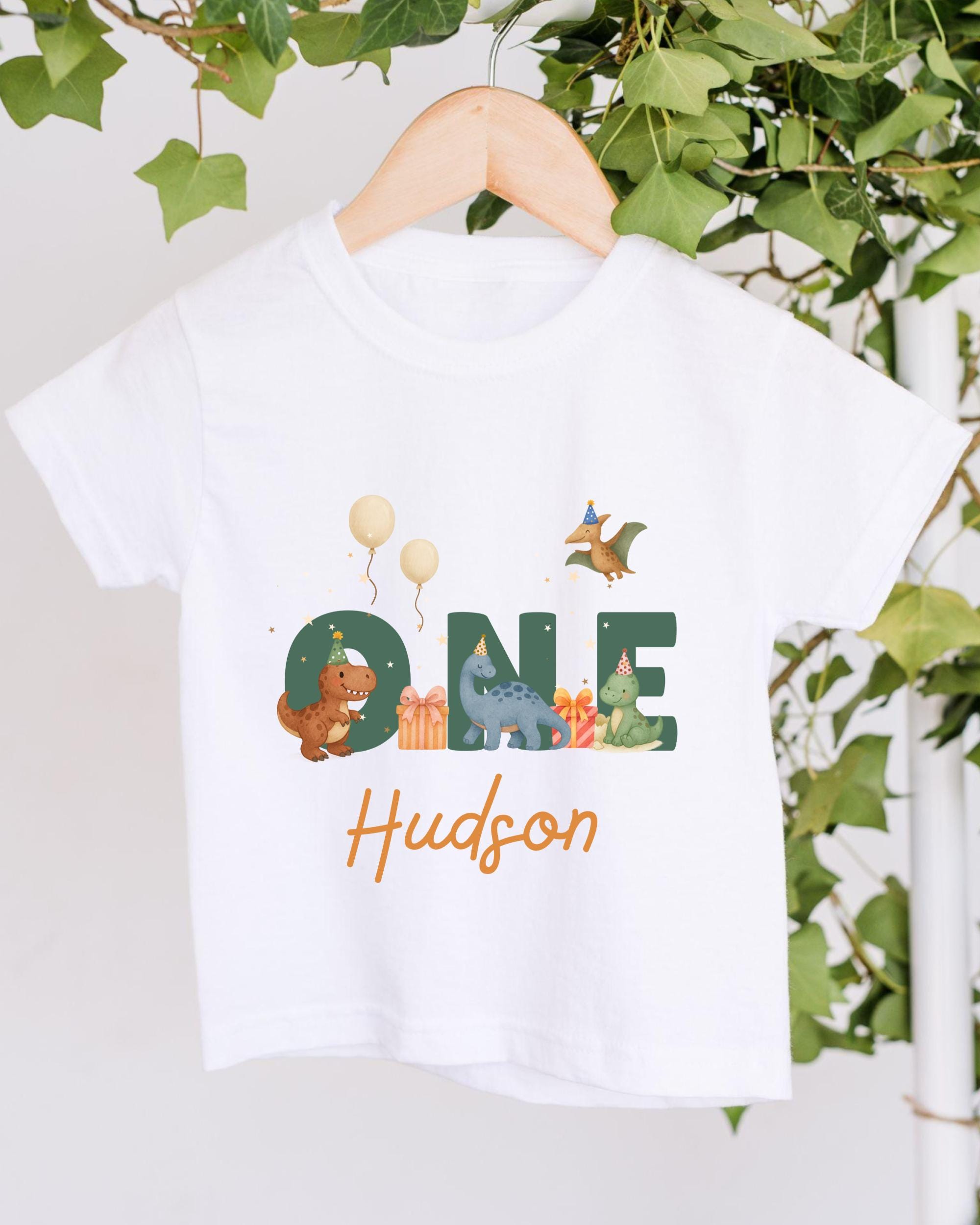 A white t-shirt with a graphic design featuring a dinosaur and other animals, along with the text "ONE Hudson" printed on it.