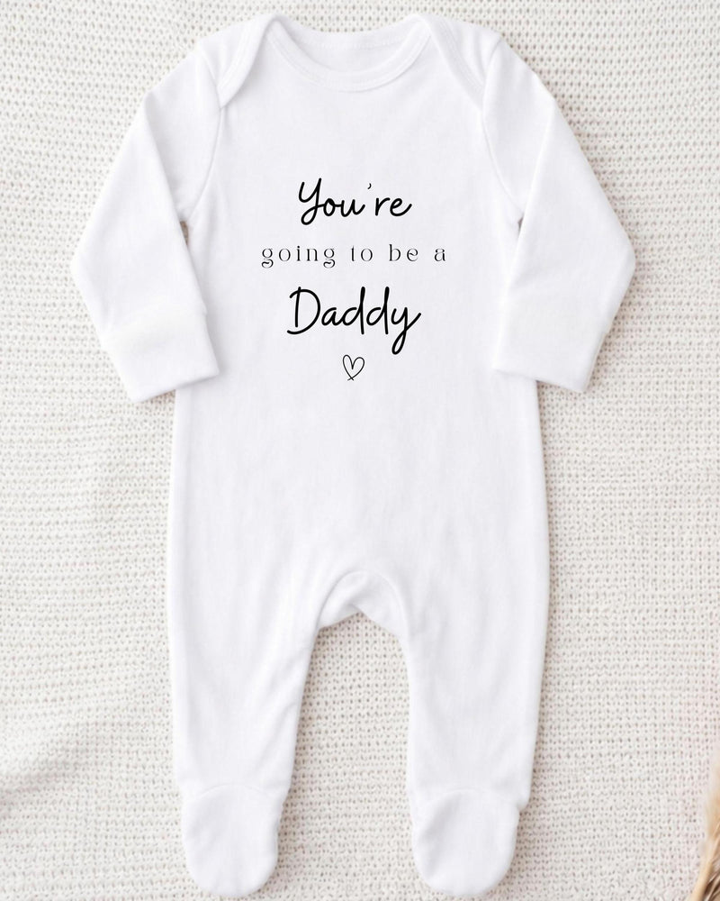 White Baby Grow with black 'You're going to be a Daddy' script and serif lettering and a small outlined heart.