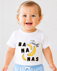 A smiling baby wearing a white t-shirt with the text "Totally Bananas" printed on it.