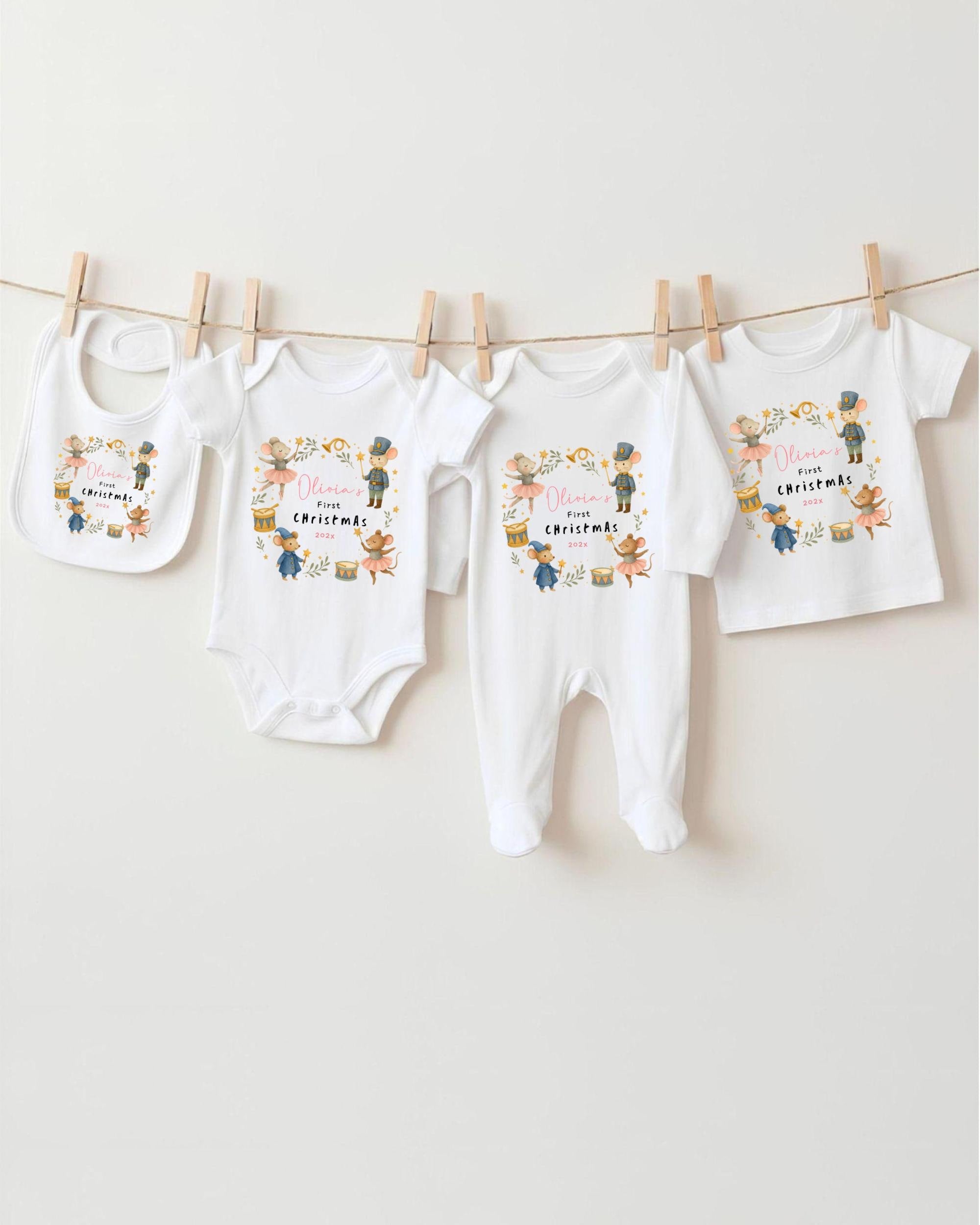 A collection of four white baby clothes, including bibs and onesies, hanging on a clothesline.