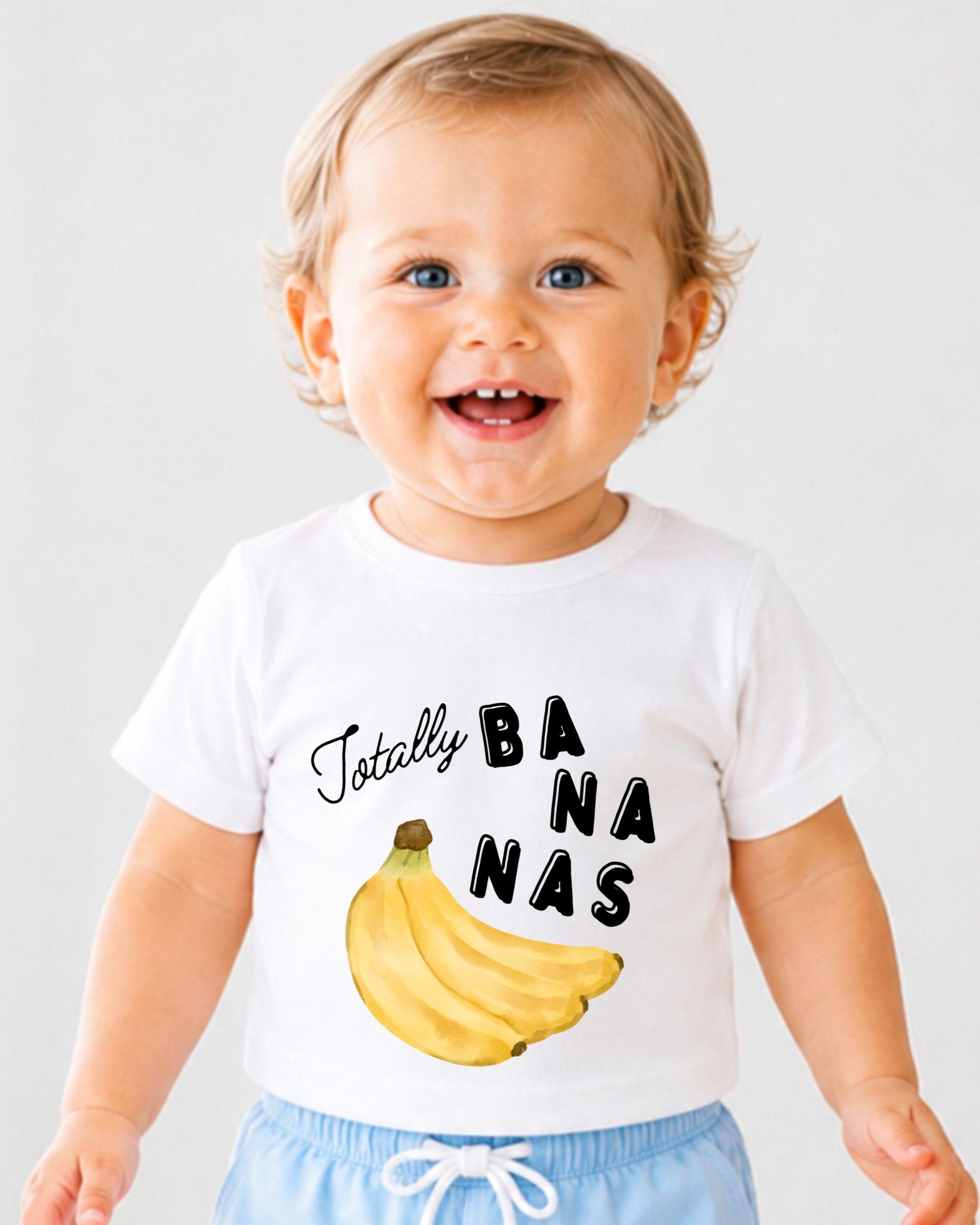 A smiling baby wearing a white t-shirt with a banana graphic and the text "Totally BANANA" printed on it.