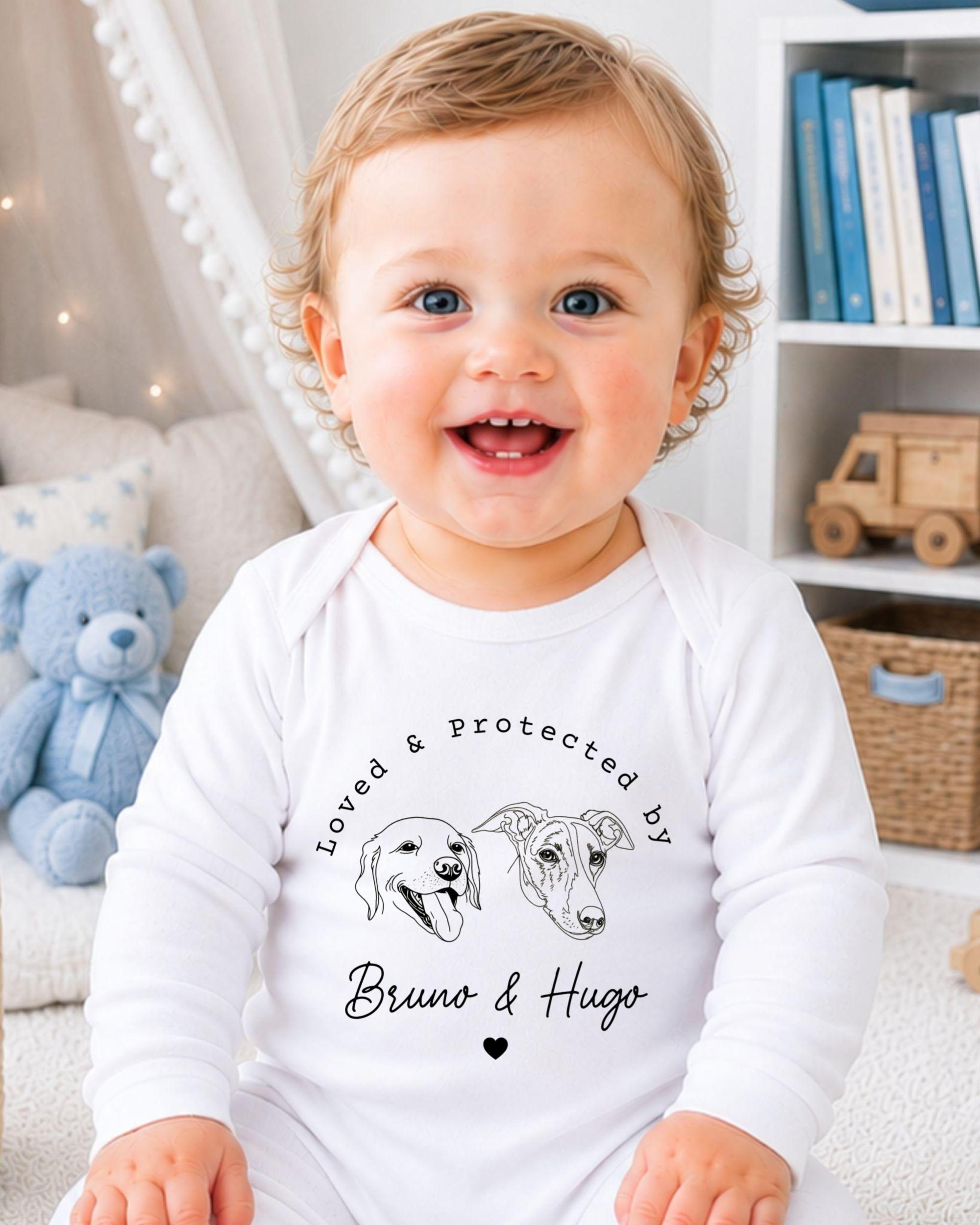 A smiling baby wearing a white onesie with a graphic of two dogs and the text "Loved & Protected by Bruno & Hugo" printed on it.