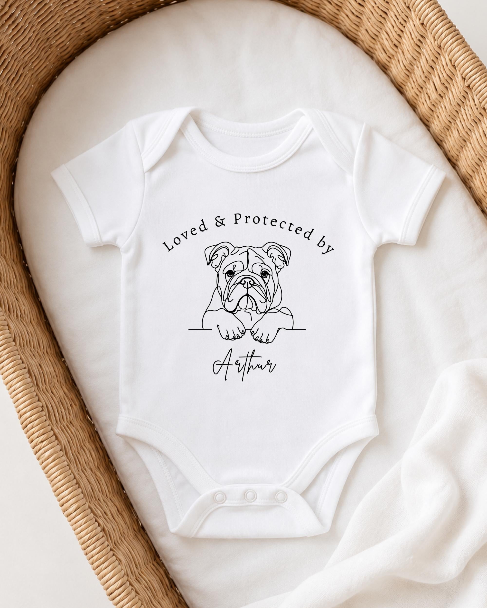 A white baby onesie with a black dog illustration and the text "Loved & Protected by Arthur" printed on it.