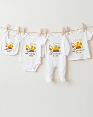 A collection of baby clothes, including onesies and pants, with a construction vehicle design printed on them.