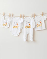 A collection of white baby clothes, including onesies and bibs, hanging on a clothesline.