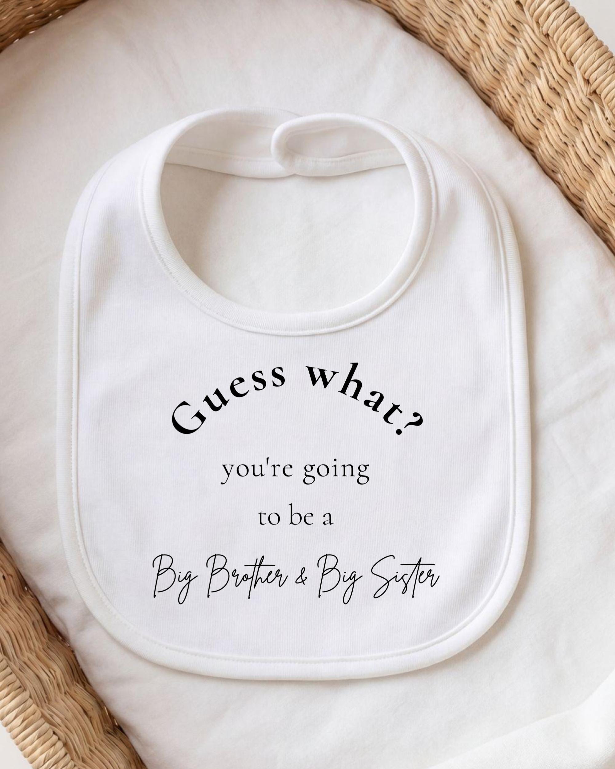 A white bib with text printed on it, placed on a white cloth.