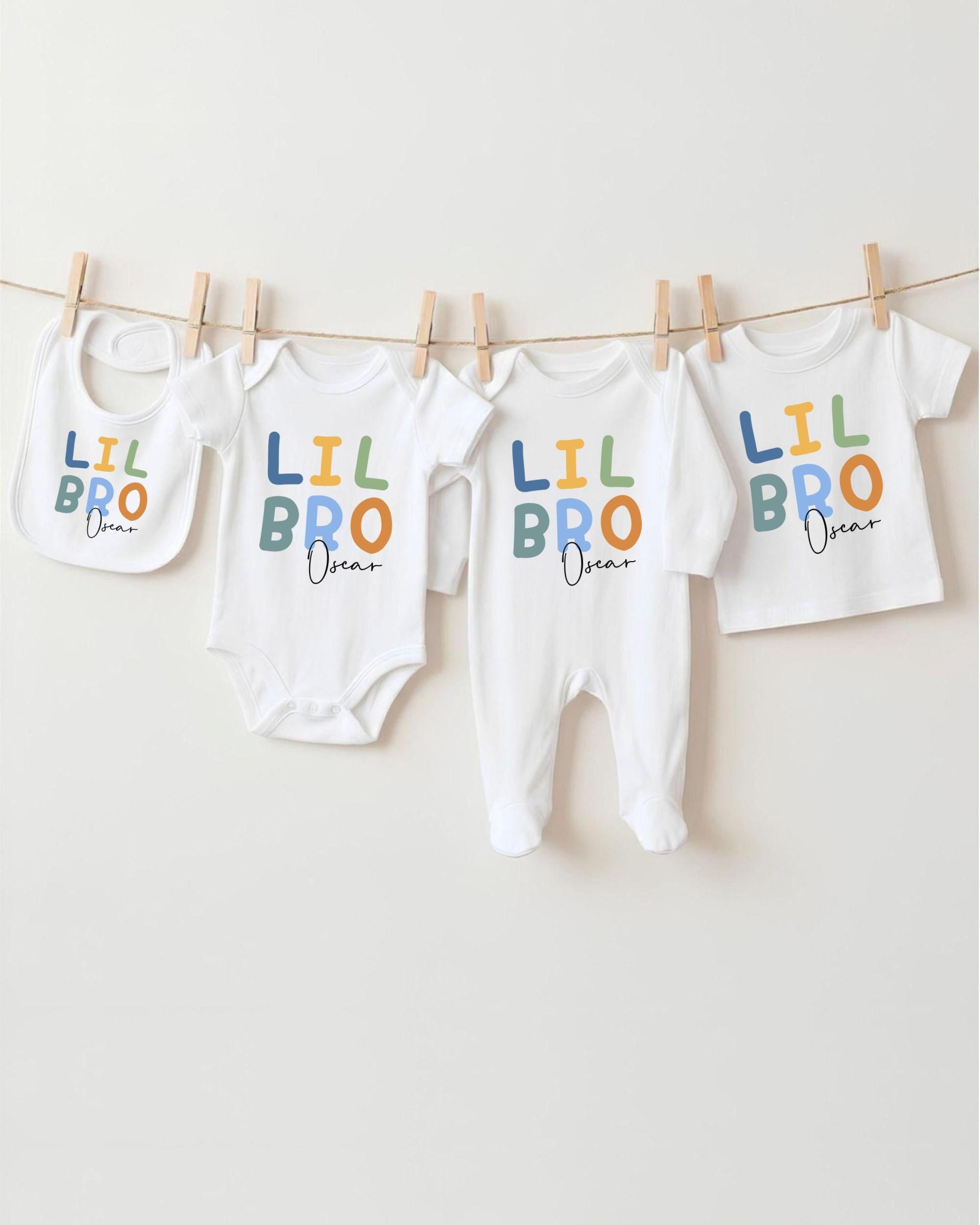A row of four white baby clothes with the text "LIL BRO Oscar" printed on them, hanging on a clothesline.
