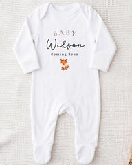 A white onesie with the text "BABY WILSON Coming Soon" printed on it, along with a small illustration of a fox.