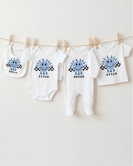 A collection of four white baby clothes, including onesies and bibs, hanging on a clothesline.