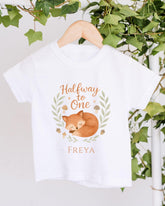 A white t-shirt with a graphic design featuring a sleeping fox and the text "Halfway to One" and "Freya" printed on it.