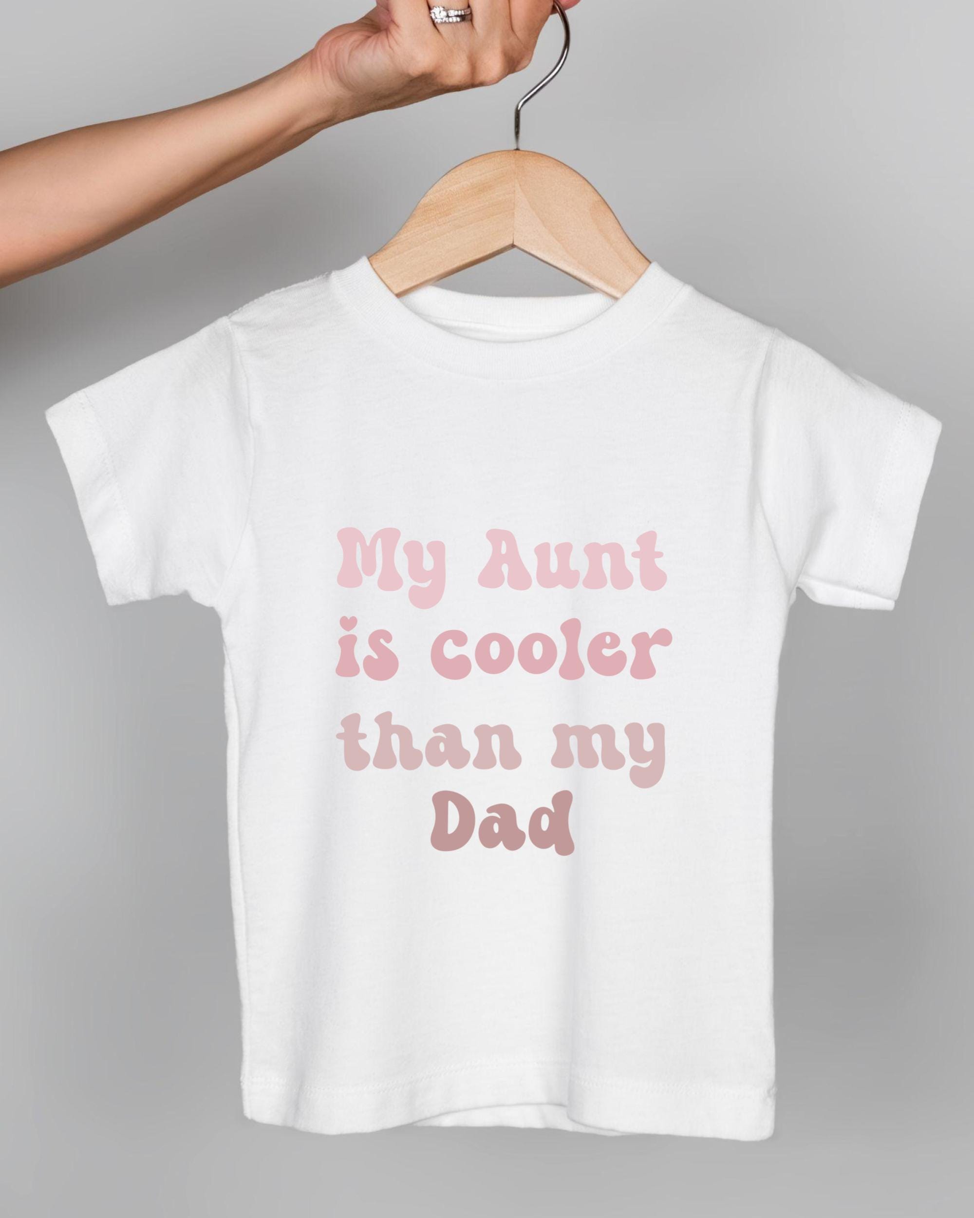 A white t-shirt with text printed on it, hanging on a wooden hanger.