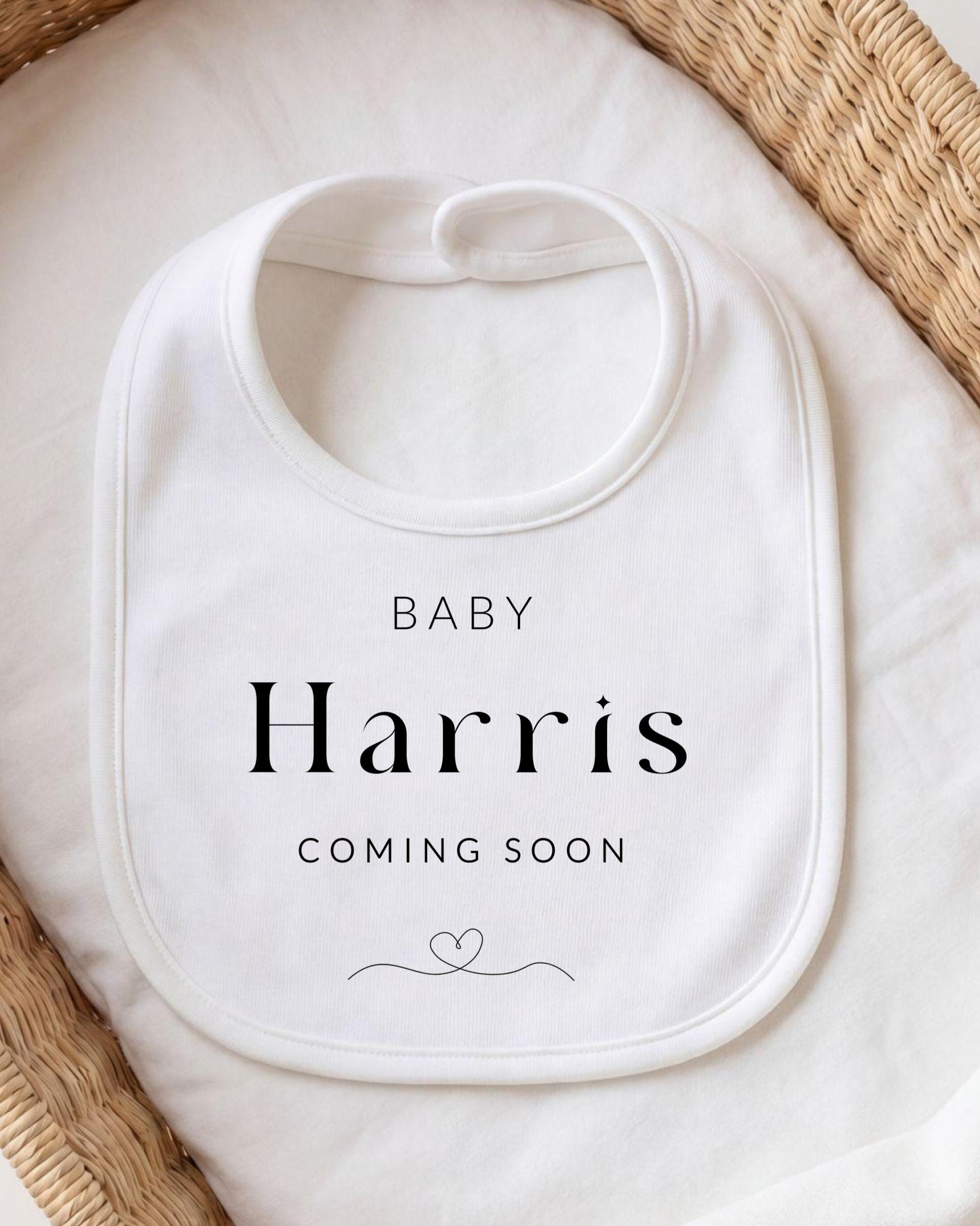 A white baby bib with the text "BABY Harris COMING SOON" printed on it.