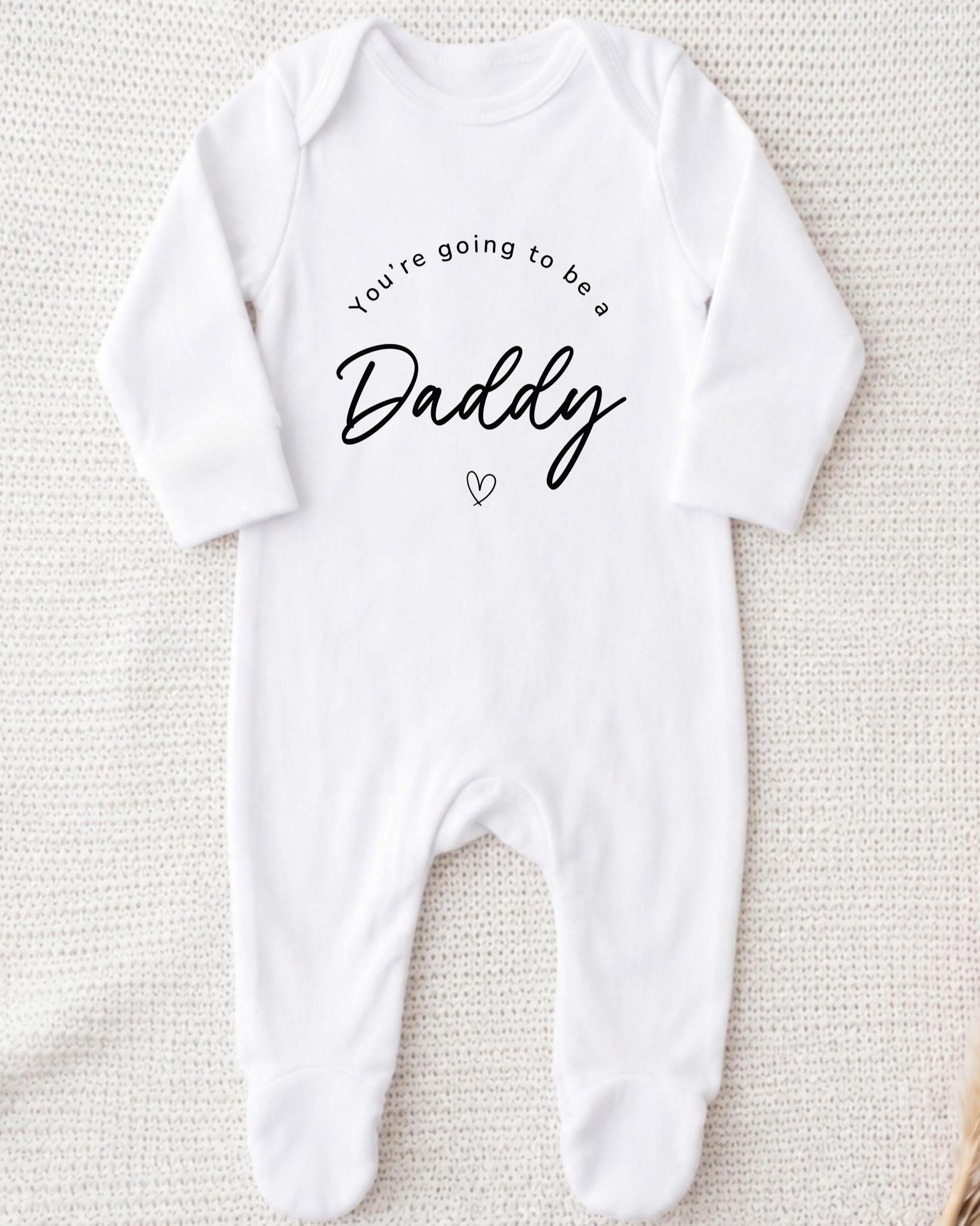 A white onesie with the text "You're going to be a Daddy" printed on it.
