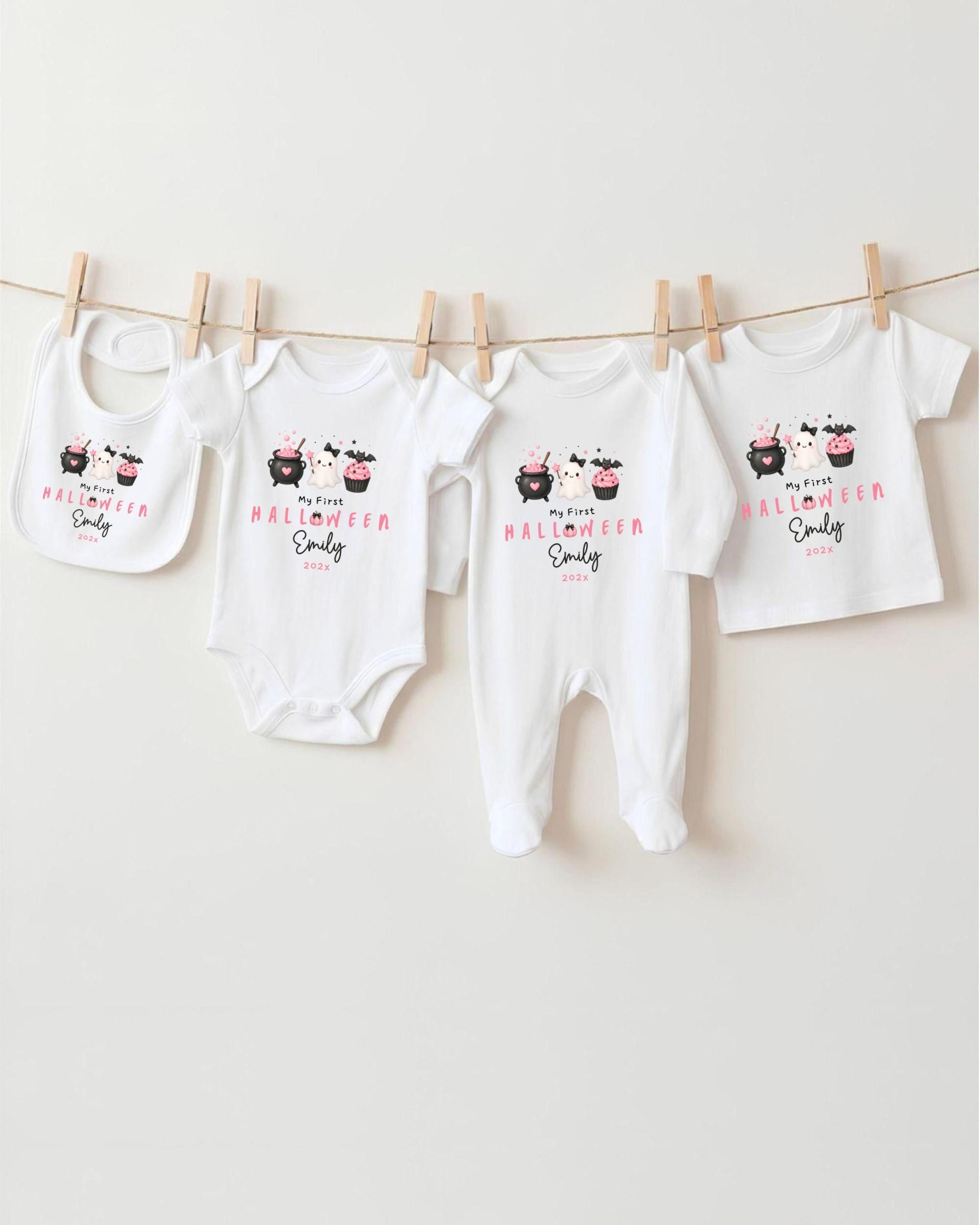 A row of four white baby clothes with Halloween-themed designs hanging on a clothesline.