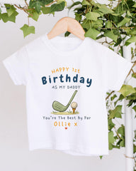 A white t-shirt with a golf-themed design and text printed on it, hanging on a wooden hanger.
