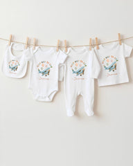A collection of baby clothes, including onesies and bibs, hanging on a clothesline.