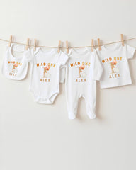 A collection of white baby clothes, including onesies and bibs, hanging on a clothesline.