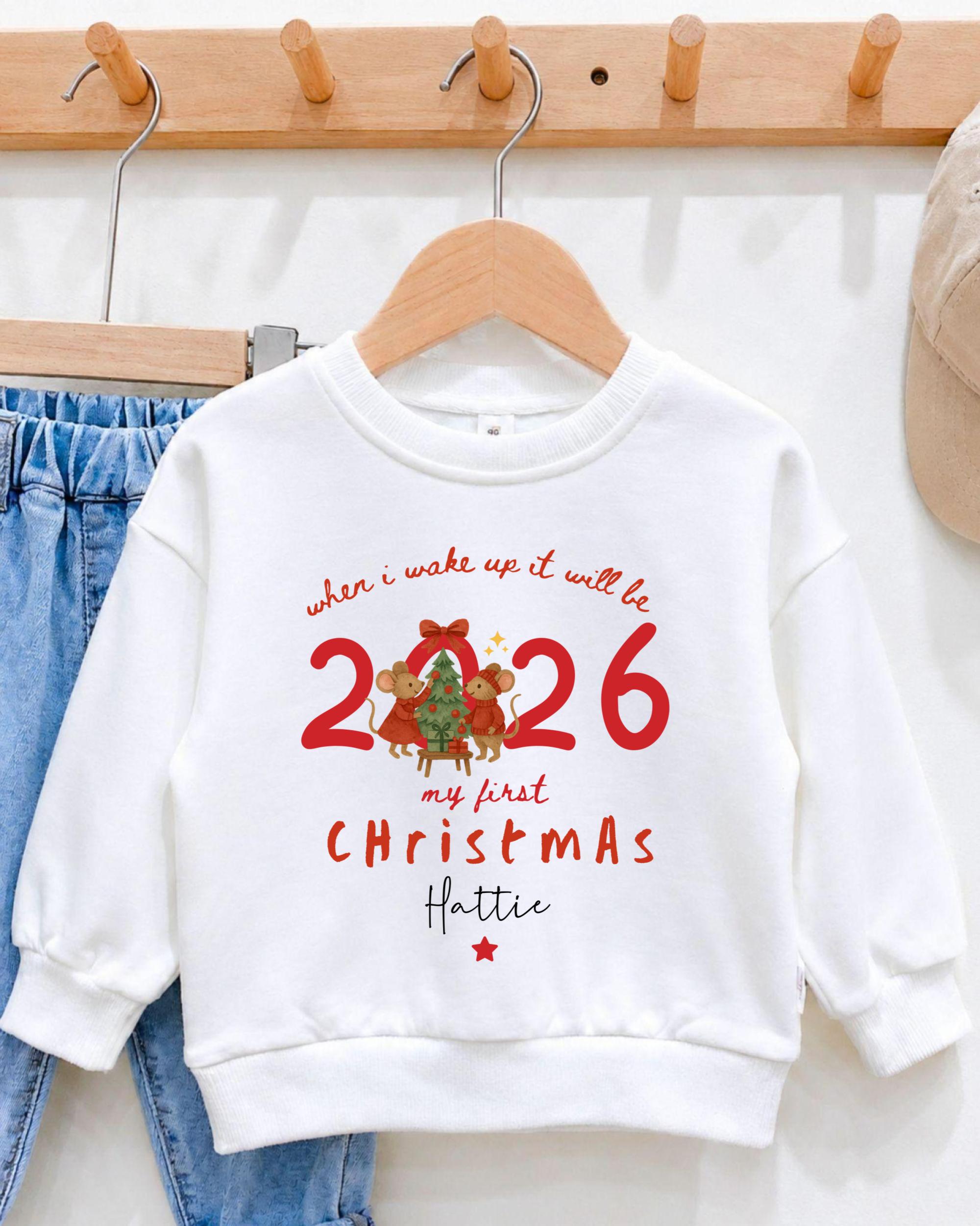A white sweater with a Christmas-themed design hangs on a wooden hanger.