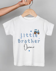 A white t-shirt with blue text and a tractor graphic, hanging on a wooden hanger.