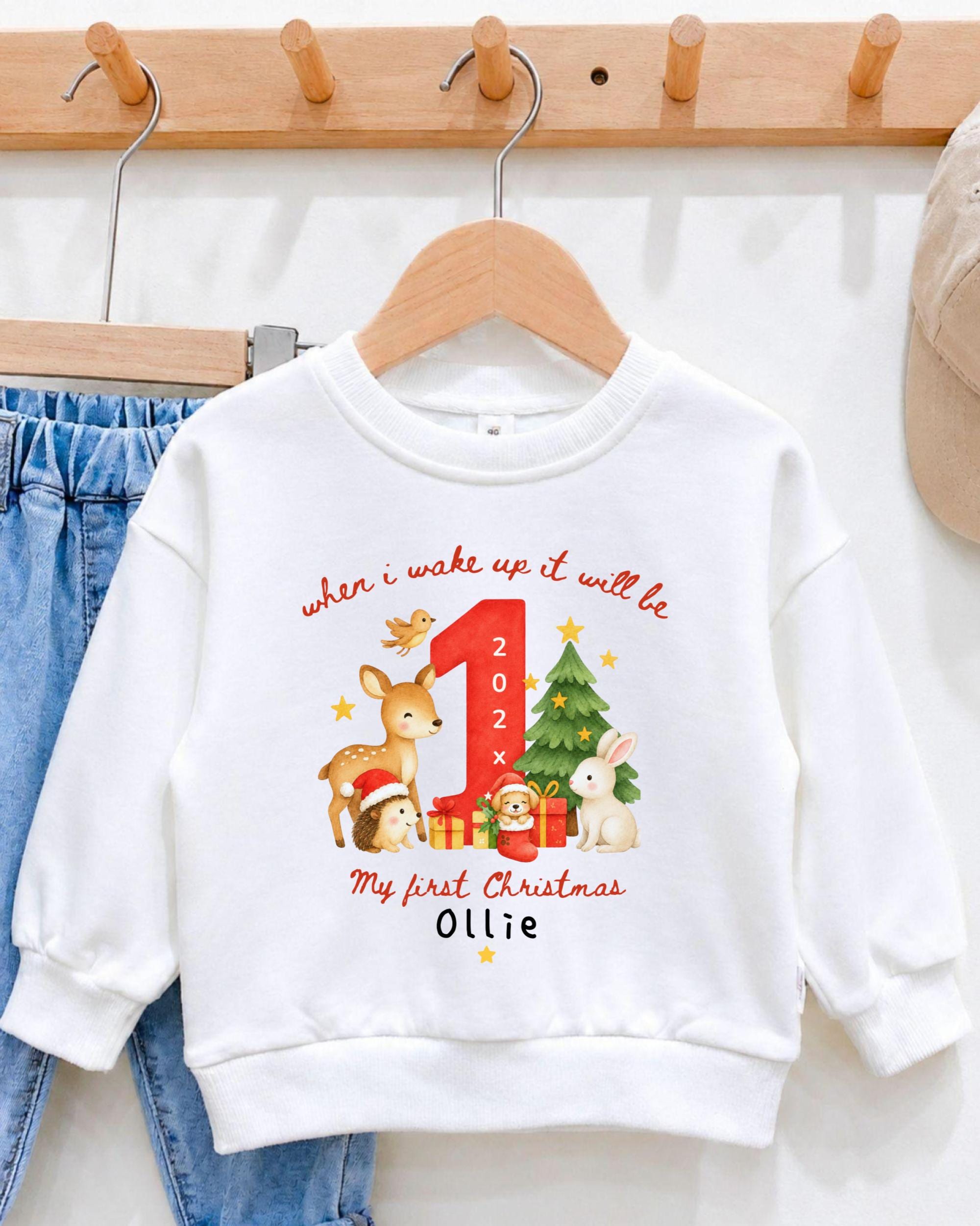 A white sweatshirt with a personalized Christmas-themed design hanging on a wooden hanger.