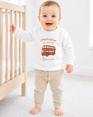 A smiling baby boy wearing a white sweatshirt with a double-decker bus design and the name "David" printed on it.