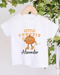 A white t-shirt with a cartoon pumpkin character and the text "Little Pumpkin Alexander" printed on it.