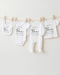 A row of white baby clothes hanging on a clothesline, with each piece labeled "Baby Box" and "Born in 2020".