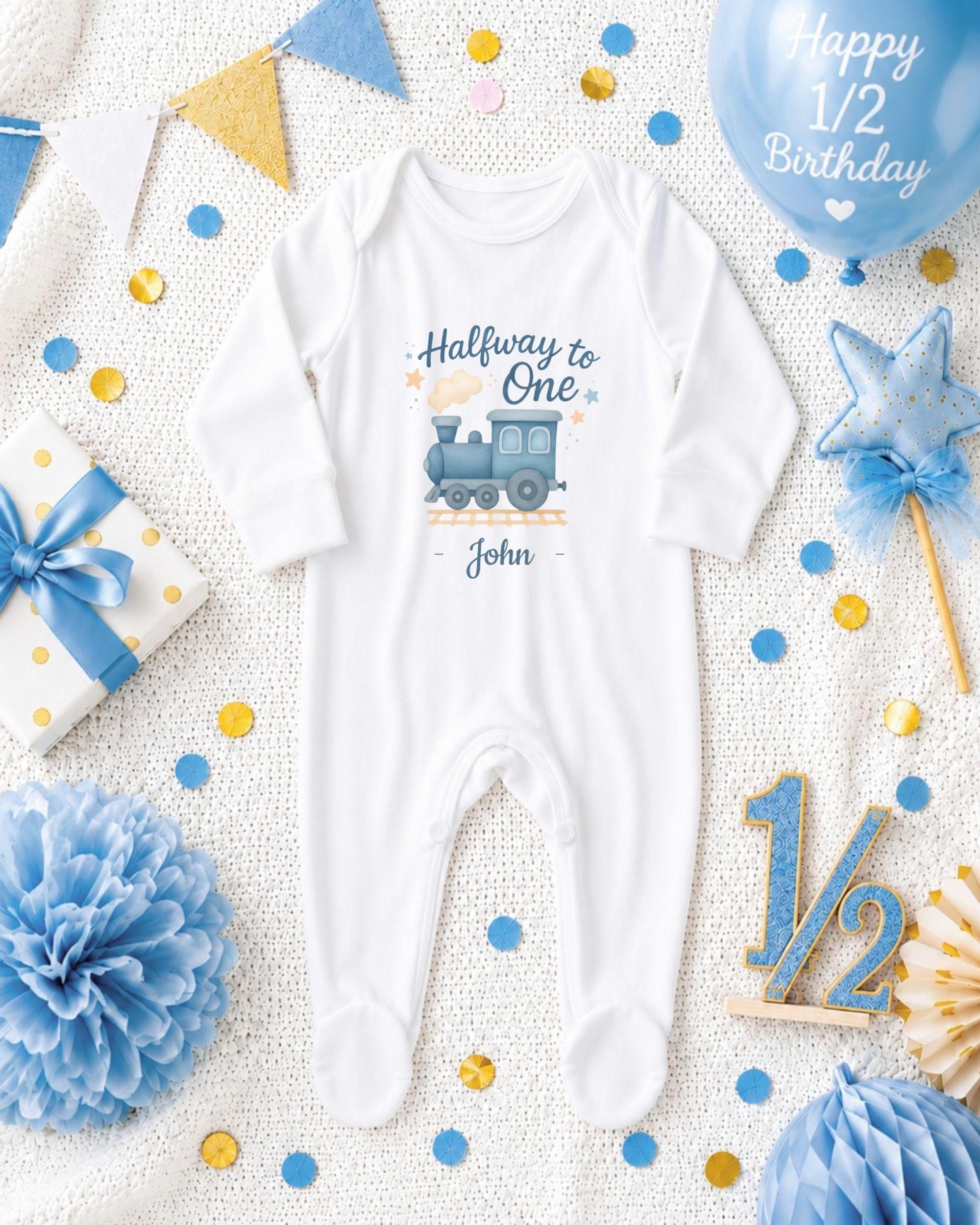 A baby onesie with a train design, surrounded by baby-themed decorations such as a balloon, confetti, and a star.
