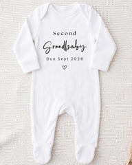 A white onesie with the text "Second Grandbaby Due Sept 2028" printed on it.