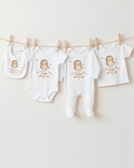 A row of four white baby clothes, including bibs and onesies, hanging on a clothesline.
