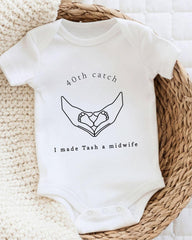 A white baby onesie with a graphic design and text printed on it.