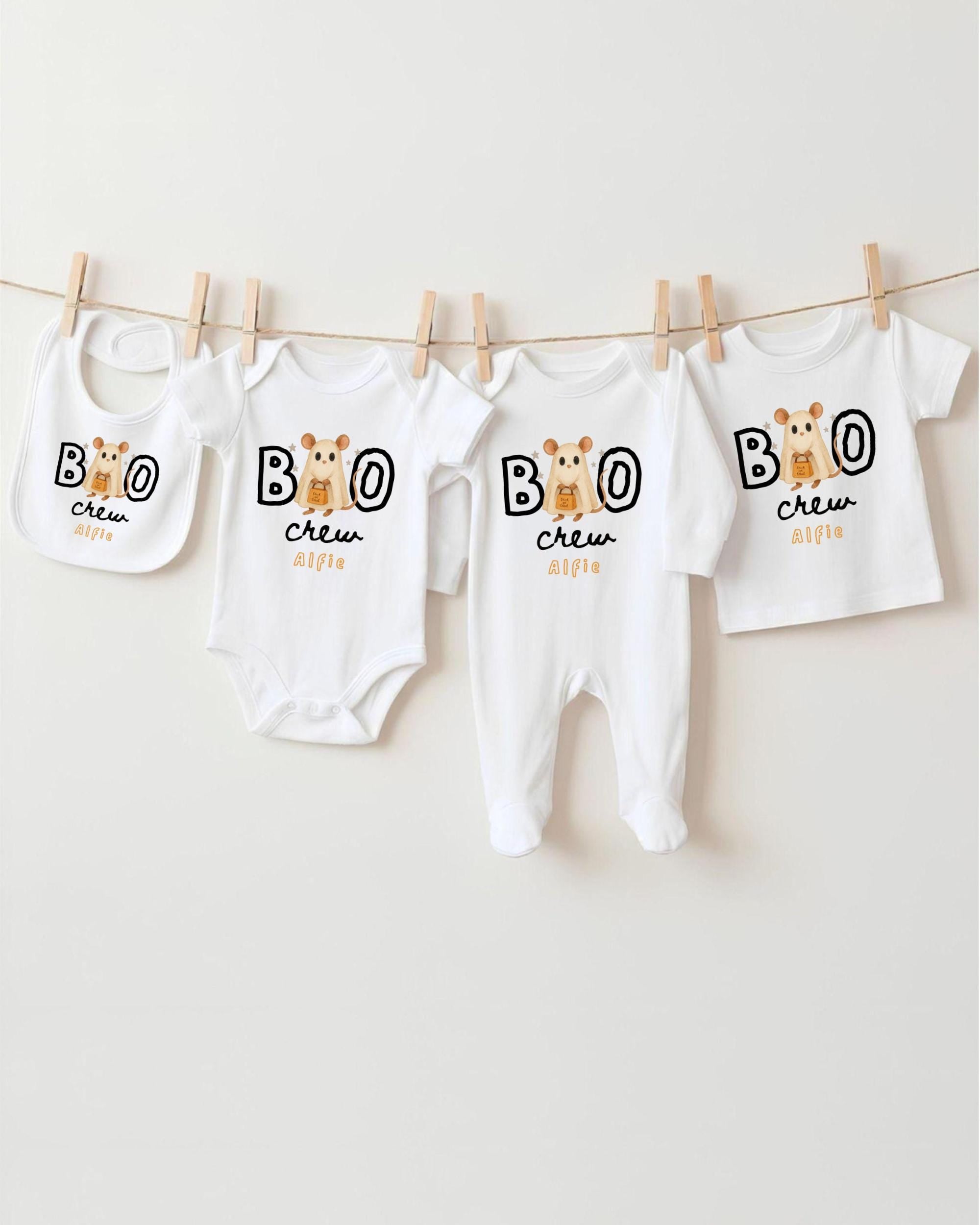 A collection of baby clothes, including onesies and bibs, hanging on a clothesline.