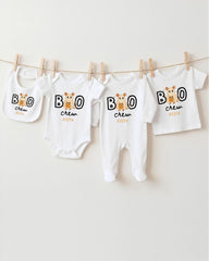A collection of baby clothes, including onesies and bibs, hanging on a clothesline.
