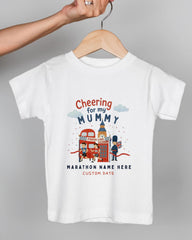 A white t-shirt with a graphic design depicting a person holding a sign that says "Cheering for my Mummy" and a red double-decker bus.