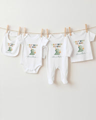 A collection of baby clothes, including onesies and bibs, hanging on a clothesline.