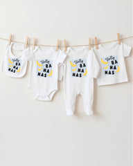 A collection of baby clothes, including onesies and bibs, hanging on a clothesline.