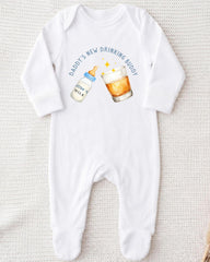 A white onesie with a graphic design on it, depicting a bottle of baby milk and a glass of beer.