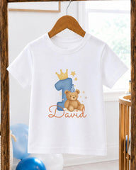 A white t-shirt with a blue number one and a teddy bear wearing a party hat, along with the text "David" printed on it.