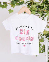 A white t-shirt with text printed on it, hanging on a wooden hanger.