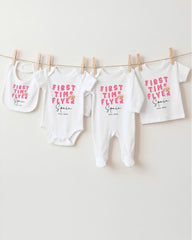 A row of four white baby clothes, including onesies and bibs, hanging on a clothesline.