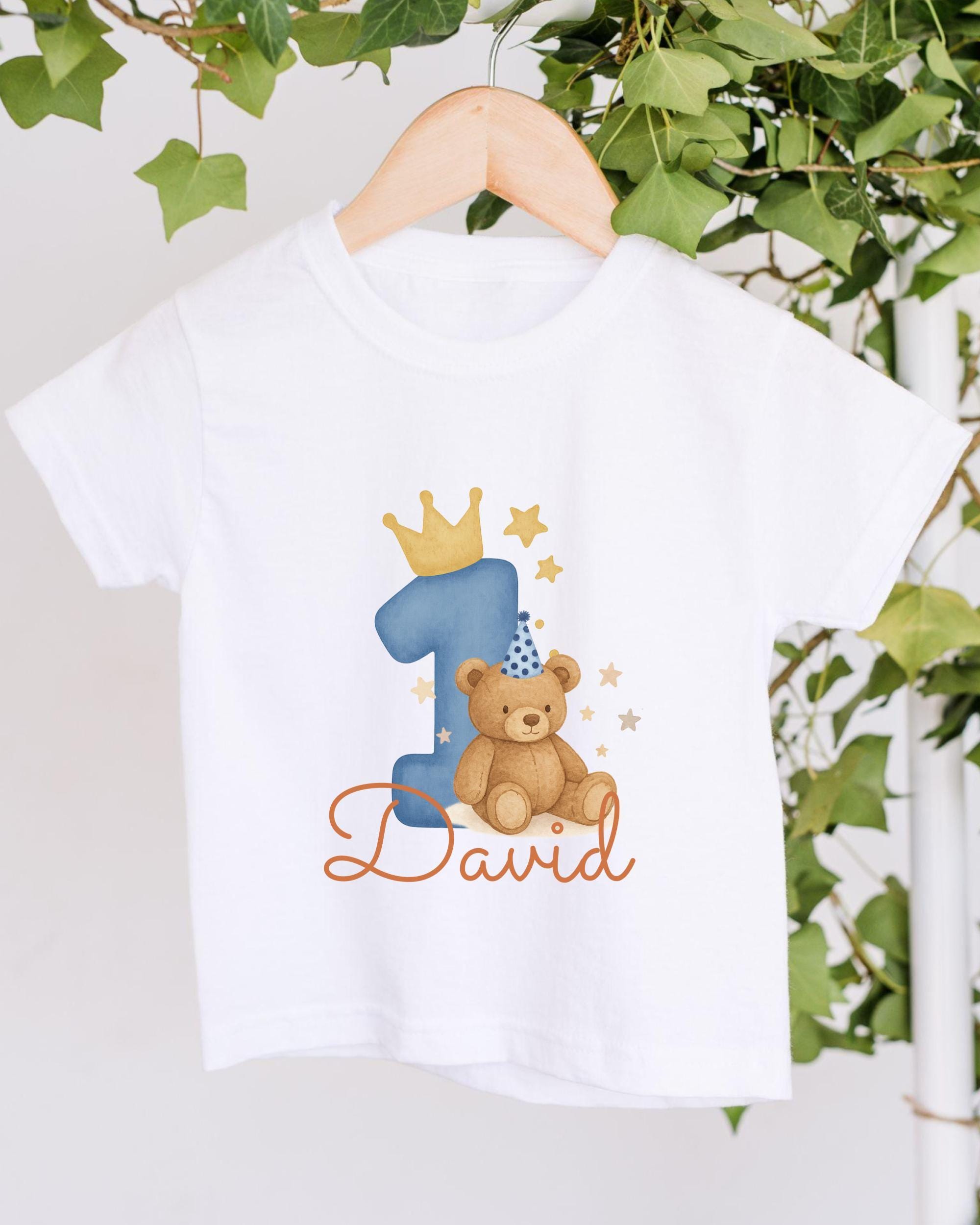 A white t-shirt with a blue number one and a teddy bear wearing a party hat, along with the text "David" printed on it.