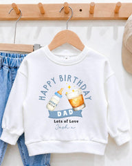 A white sweatshirt with a birthday message printed on it, hanging on a wooden hanger.