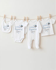 A row of baby clothes, including onesies and bibs, hanging on a clothesline.