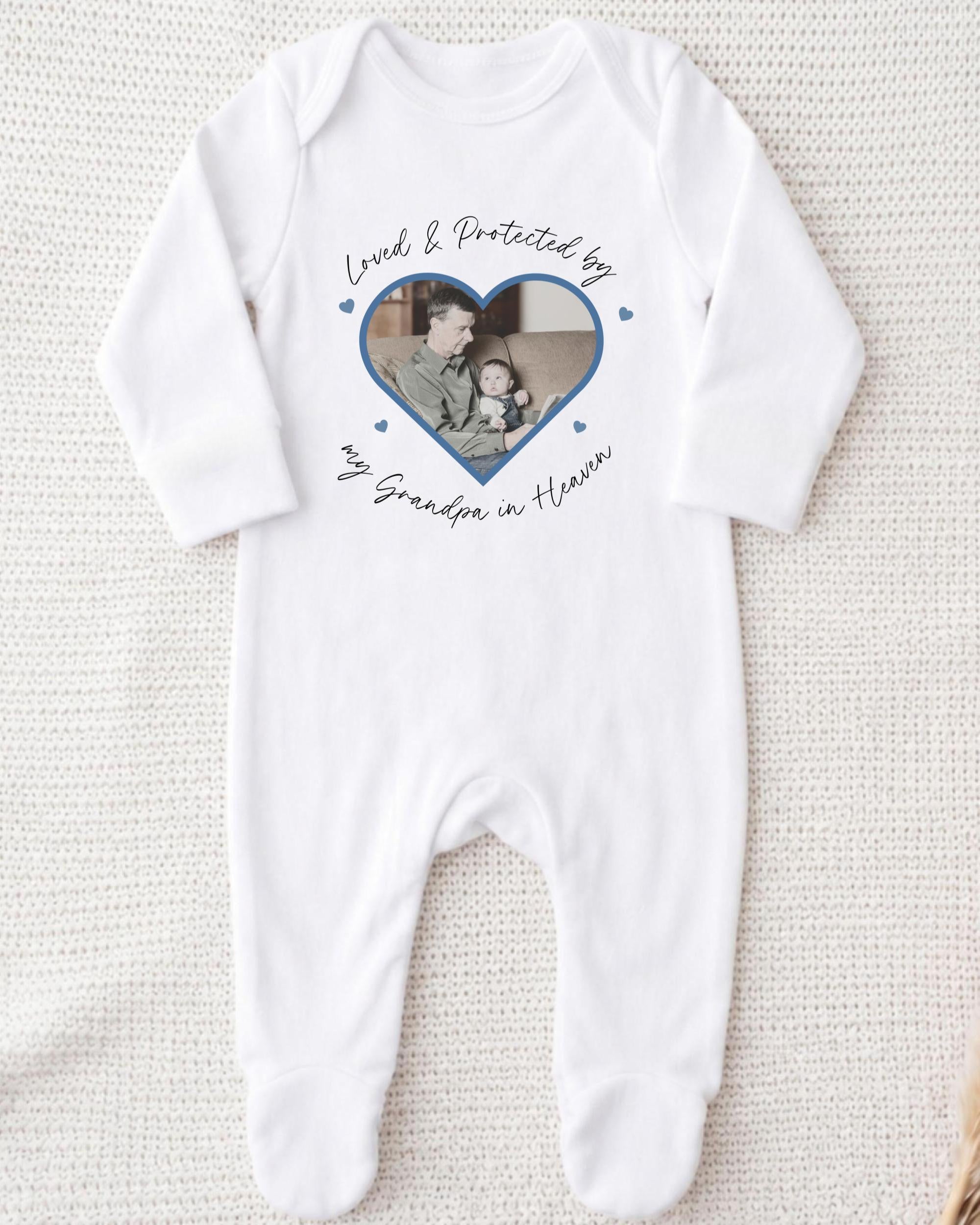A white onesie with a heart-shaped photo of a man and a child printed on it, along with the text "Loved & Protected by my Grandpa in Heaven".