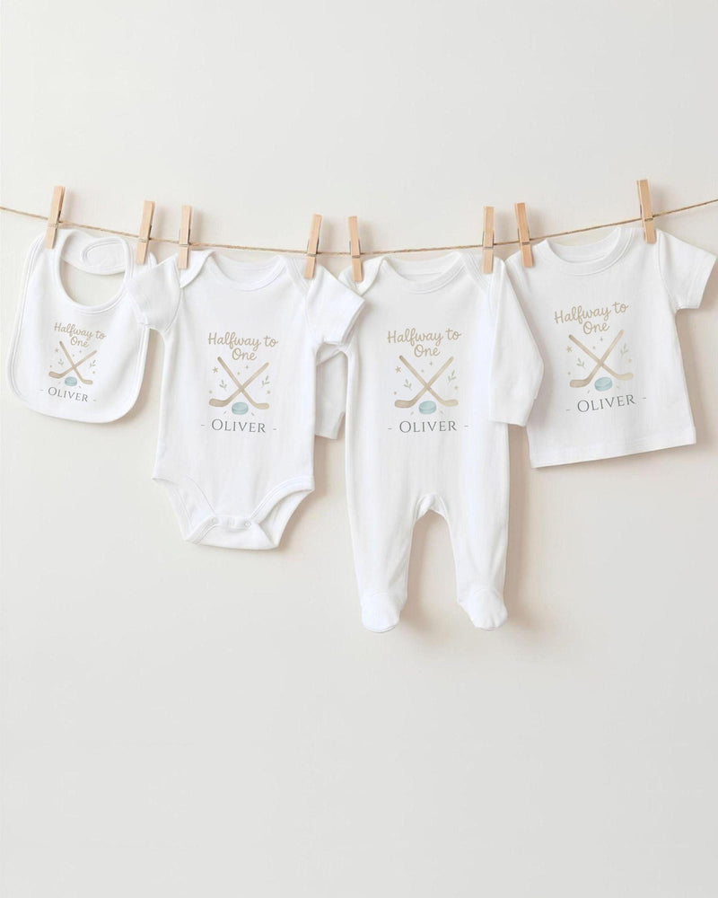 A row of four white baby clothes, including onesies and bibs, hanging on a clothesline.