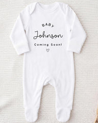 A white onesie with the text "BABY Johnson Coming Soon" printed on it.